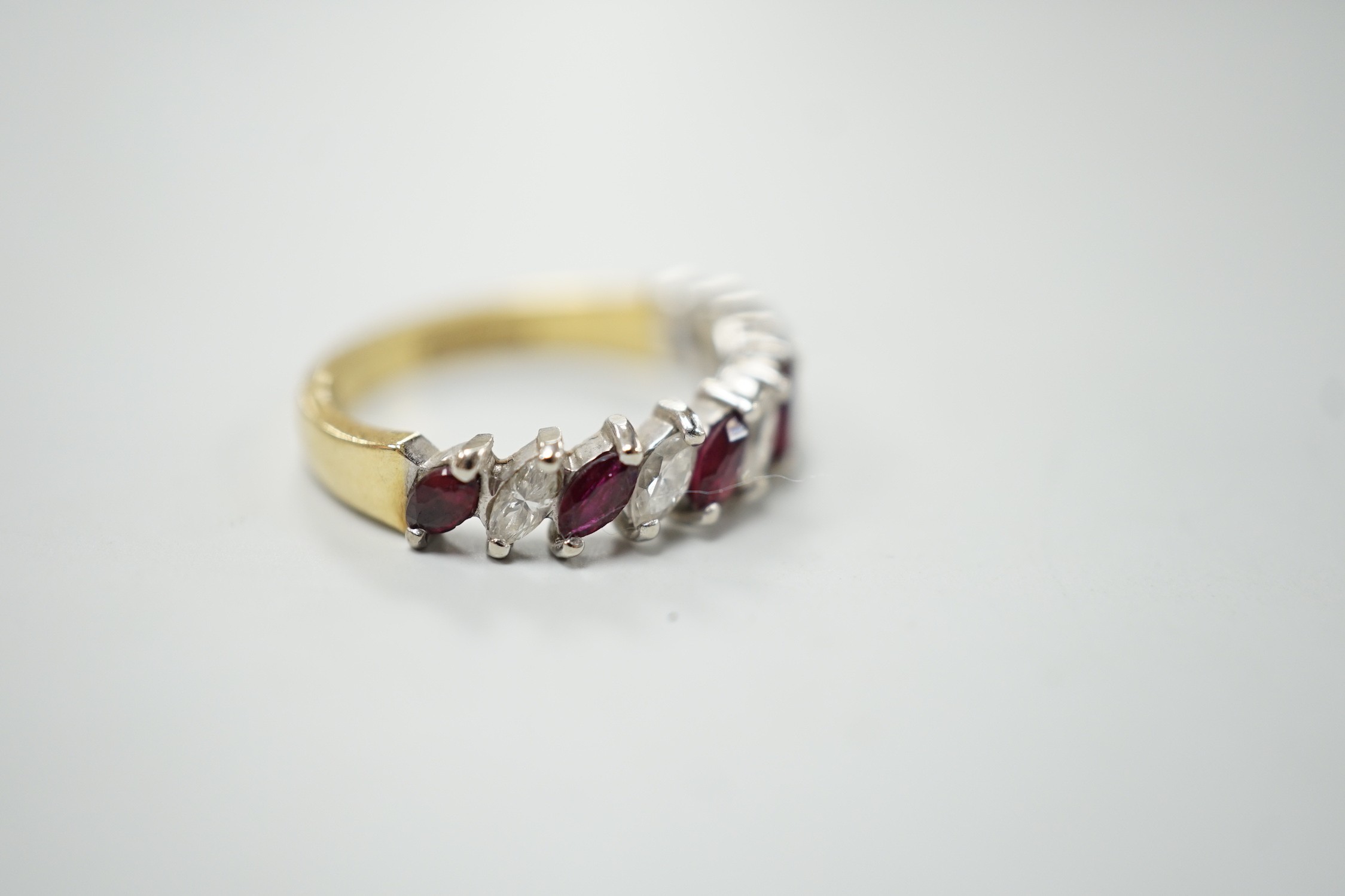A modern 18ct gold and eleven stone marquise cut ruby and diamond set half hoop ring, size L, gross weight 3.5 grams.